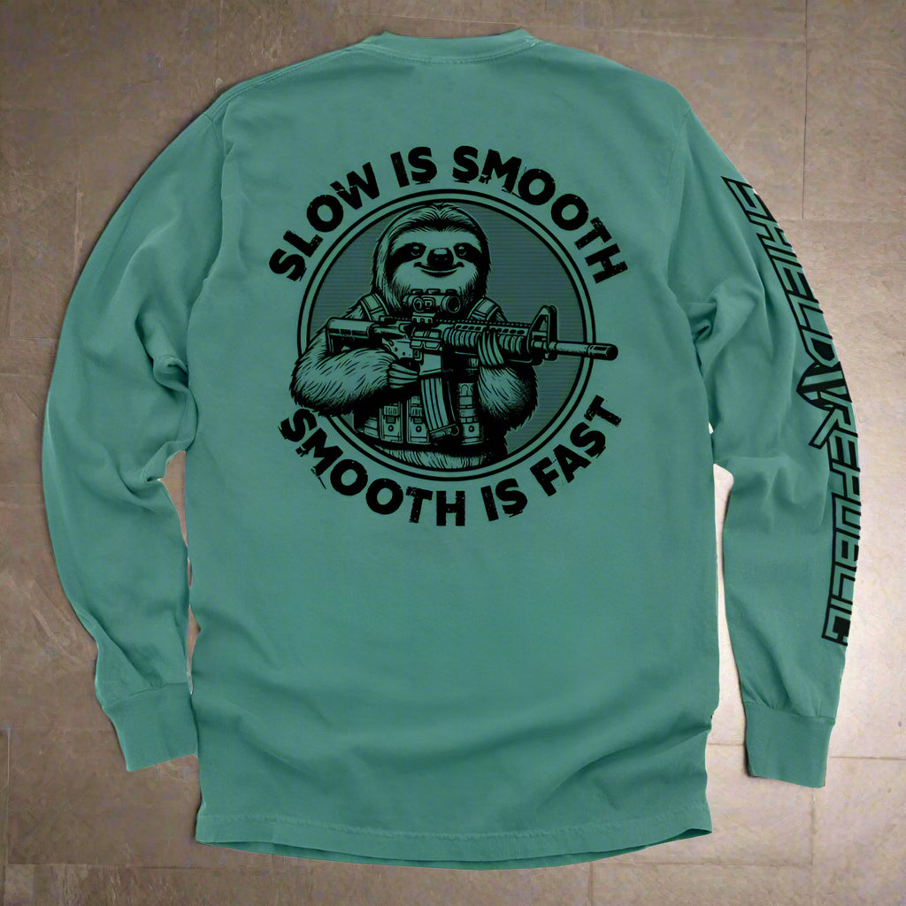 Teal long-sleeve shirt with a graphic of a sloth holding a rifle and text 'Slow is Smooth, Smooth is Fast' on a white background.