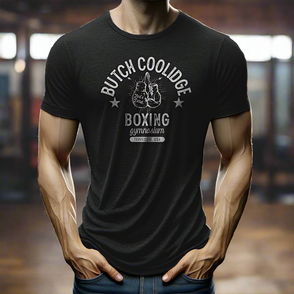 man wearing a t-shirt in a rustic old steamy boxing gym at magic hour